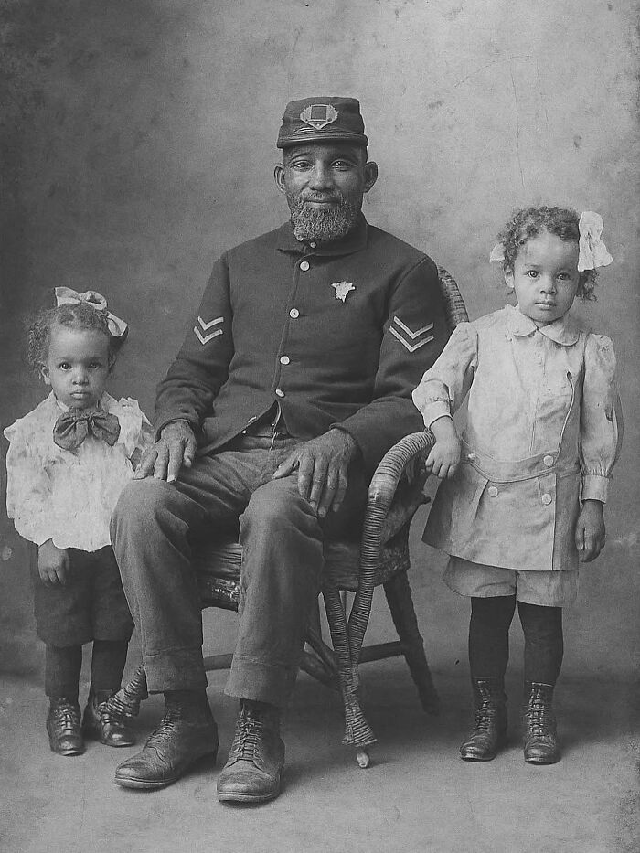 Historic black and white photograph of an African American soldier with two young children, reflecting the history of humanity.
