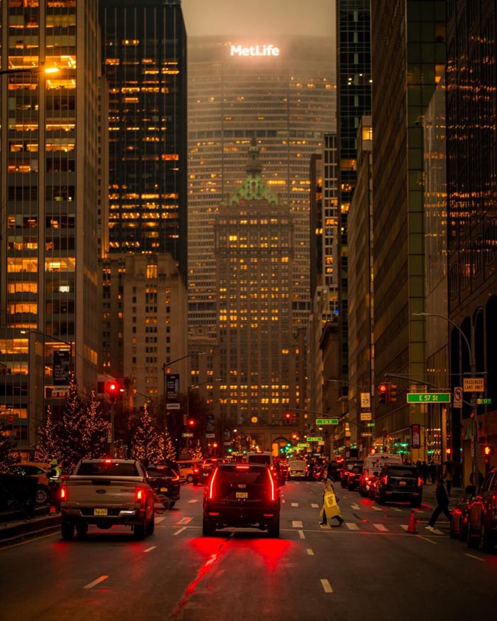 City street at dusk with traffic and lit buildings, illustrating countries that sleep the most in OECD time use data.