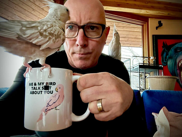 Man wearing glasses holding a mug with a bird, illustrating movie set workers sharing diva stars they've worked with.
