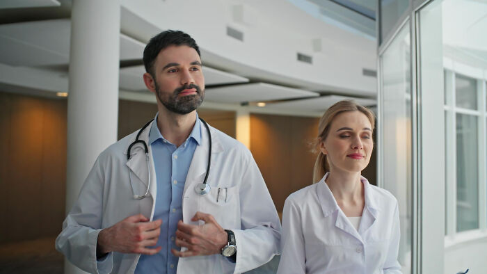 Two doctors in white coats walking in a hospital hallway, illustrating examples of a doctor doing something unethical with a patient.