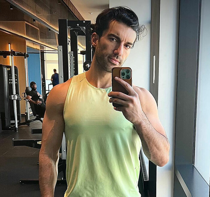 Man in gym taking selfie in mirror, wearing yellow sleeveless shirt, highlighting Kim Kardashian Taylor Swift comments suspicion.