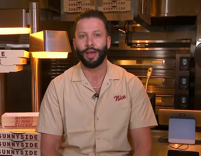 Pizzeria owner with beard in kitchen, known for his salty replies to harsh online reviews at Sunnyside Pizzeria. Pizzeria owner with beard in kitchen, known for his salty replies to harsh online reviews at Sunnyside Pizzeria.