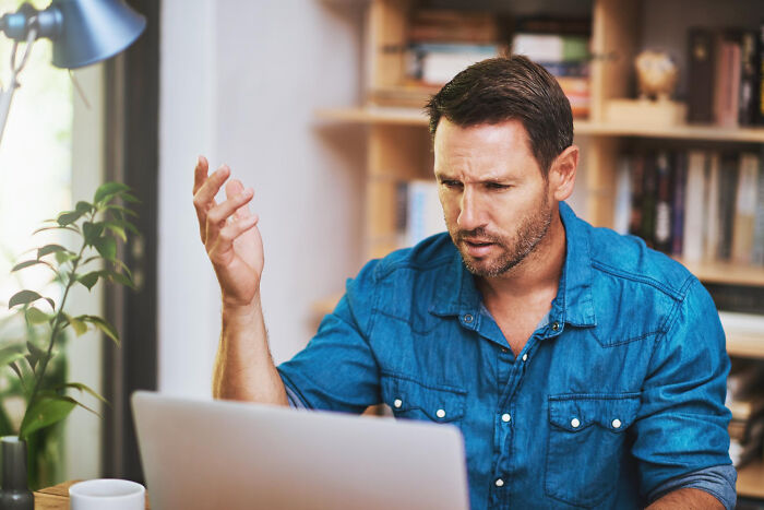 Man in blue shirt confused while using laptop, reacting to moments so ridiculous people thought they were being pranked