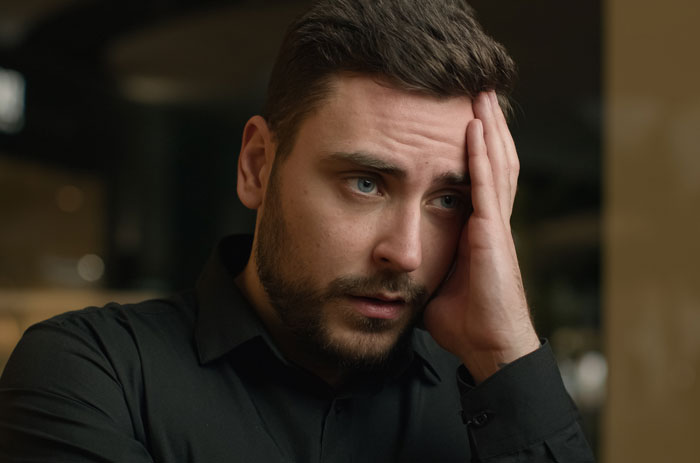 Young man in a black shirt looking stressed and worried while thinking about emptying father's estate and will issues. Young man in a black shirt looking stressed and worried while thinking about emptying father's estate and will issues.