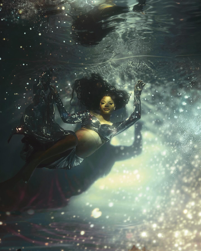 Pregnant woman floating underwater in flowing gown amid sparkling light and bubbles, creative maternity photoshoot