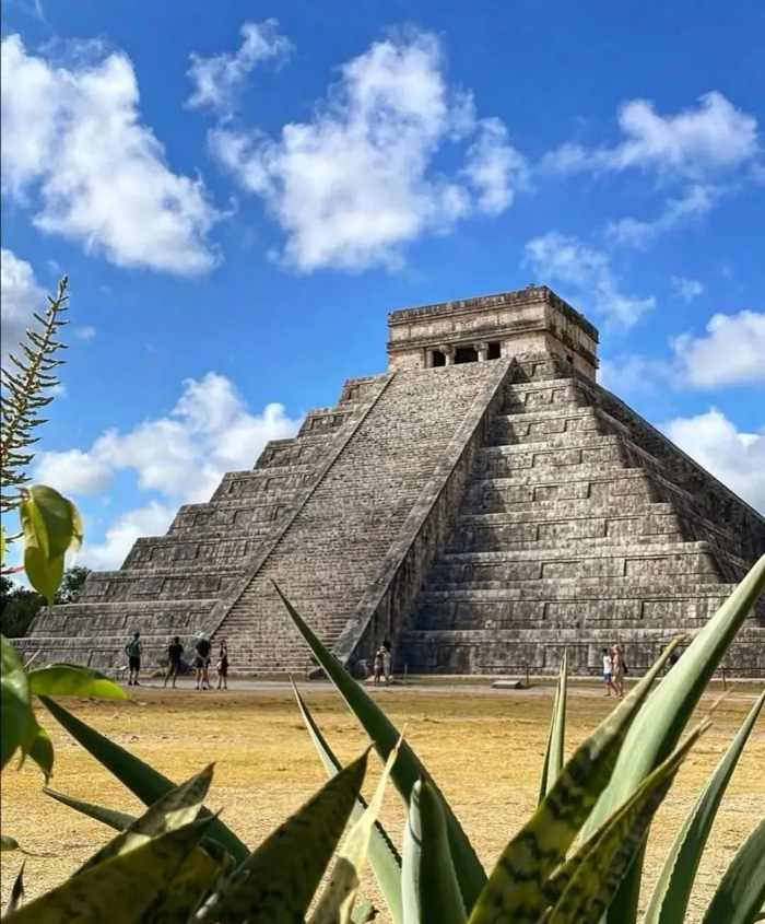 El Castillo pyramid at Chichen Itza with agave plants and visitors under blue sky, illustrating fun facts about Mexico