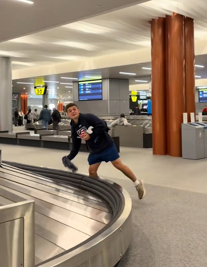 Passenger at baggage claim grabbing underwear as items appear one by one on luggage carousel in airport terminal.