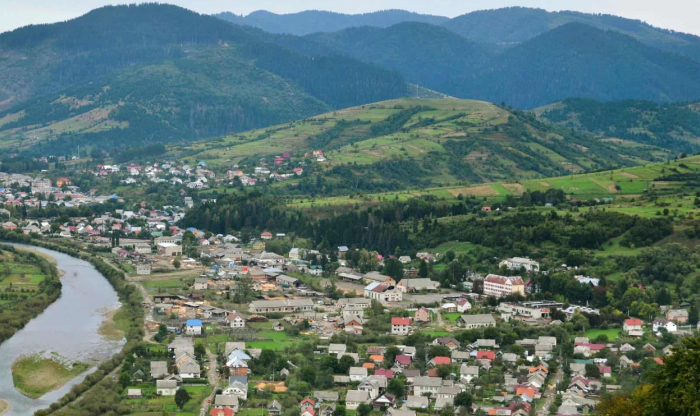 Aerial view of a village surrounded by green hills and mountains, illustrating one of the forbidden places on Earth.