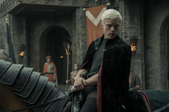 Actor in medieval armor and cloak holding a sword on horseback in a scene from A Knight Of The Seven Kingdoms ahead of Season 1.