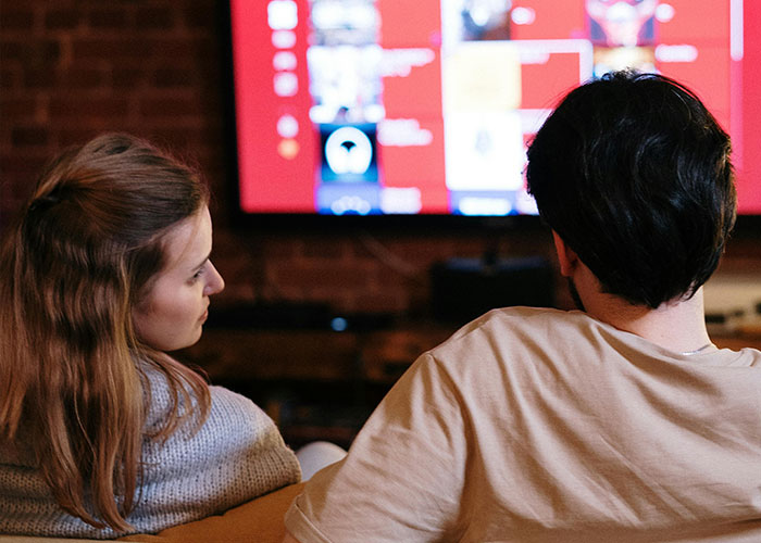 Two people sitting on a couch watching TV, illustrating neurodivergent experiences shared by 116 people.