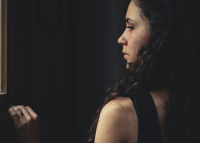 Woman with curly hair looking out window, reflecting on a romantic getaway situation involving friend and husband conflict. Woman with curly hair looking out window, reflecting on a romantic getaway situation involving friend and husband conflict.
