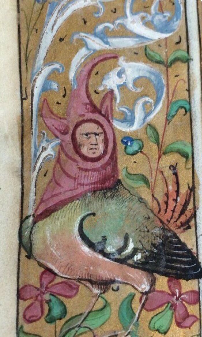 Medieval painting of a bird with a human face wearing a whimsical hat surrounded by decorative floral patterns.