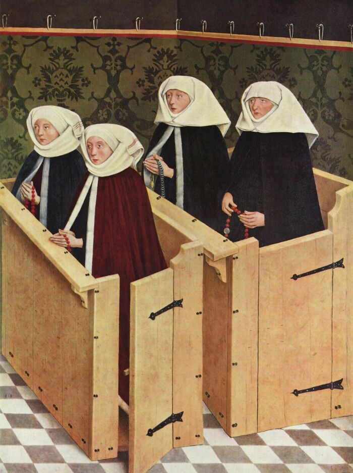 Four medieval women in robes and white headdresses holding rosary beads inside wooden confessionals in a medieval painting.