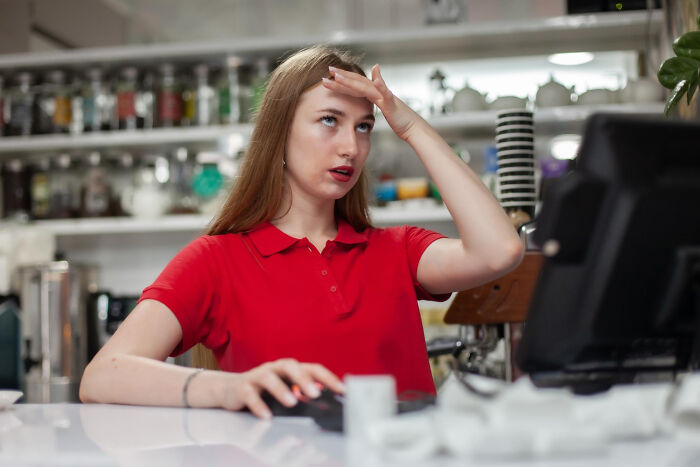 Woman in red shirt looking frustrated at computer, illustrating weird and satisfying situations with a not my problem attitude.