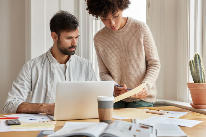 Two colleagues reviewing documents by laptop in a home office, capturing moments that hit people harder than expected.