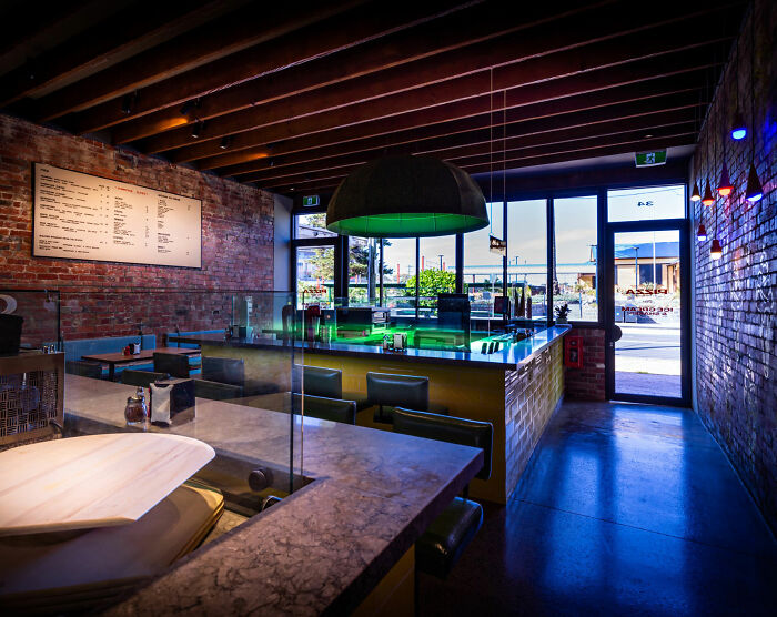Interior of a modern pizzeria with brick walls and a menu board, related to a pizzeria owner and online reviews. Interior of a modern pizzeria with brick walls and a menu board, related to a pizzeria owner and online reviews.