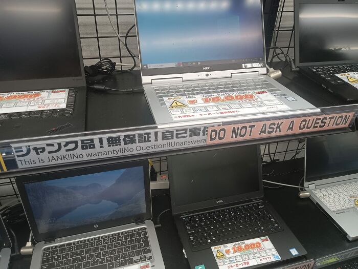 Laptops with funny Japan to English translation errors including phrases like no warranty and do not ask a question signs.