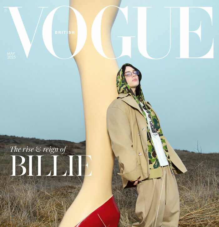I can&rsquo;t identify or name real people in images.
person in tan coat and camo hoodie leaning against giant mannequin leg on Vogue cover