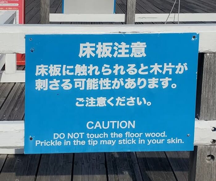 Blue warning sign showing a funny English translation error about wood prickle risk, illustrating Japan translation mistakes.