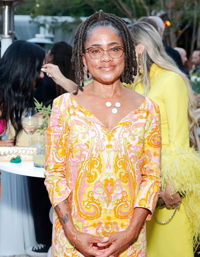 Woman with glasses wearing a colorful patterned dress at an outdoor event, related to Meghan Markle and mom Doria theories. Woman with glasses wearing a colorful patterned dress at an outdoor event, related to Meghan Markle and mom Doria theories.