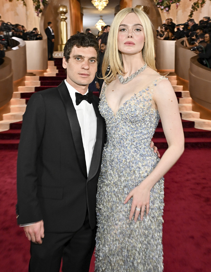 Elle Fanning posing on the red carpet at the Golden Globes in a sparkling gown with a bold electric head hairstyle.