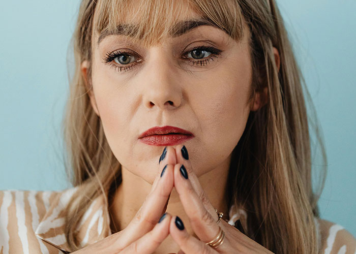 Woman with blonde hair and red lipstick deep in thought, representing neurodivergent habits and behaviors reflection.