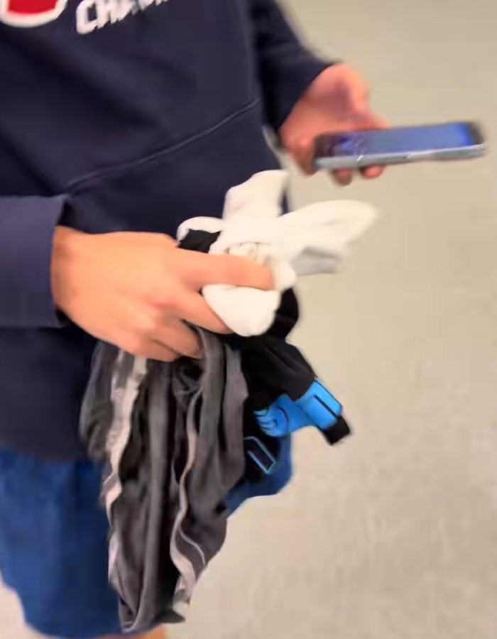 Passenger holding multiple pairs of underwear after they appeared one by one on baggage claim, causing viral attention.