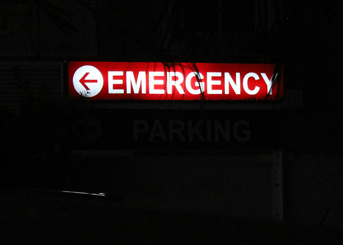 Emergency sign glowing at night outside hospital representing worst things medical professionals have said to patients.