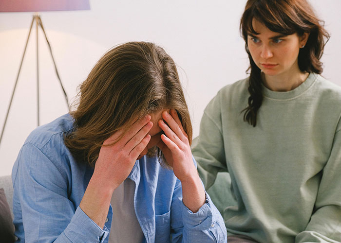 A young man showing signs of distress while a concerned woman listens, highlighting neurodivergent experiences.