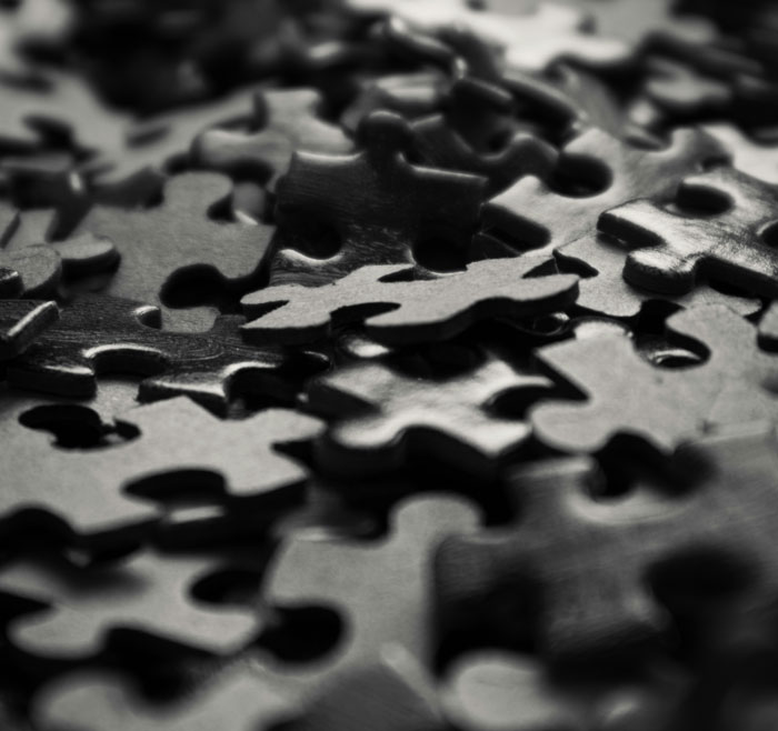 Close-up of black puzzle pieces scattered, symbolizing moments of smart thinking that feel borderline creepy.