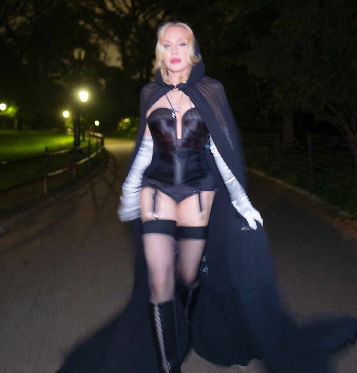 Madonna wearing a black corset and cape walking at night in a raunchy Dolce & Gabbana ad with younger men and c****h shot.