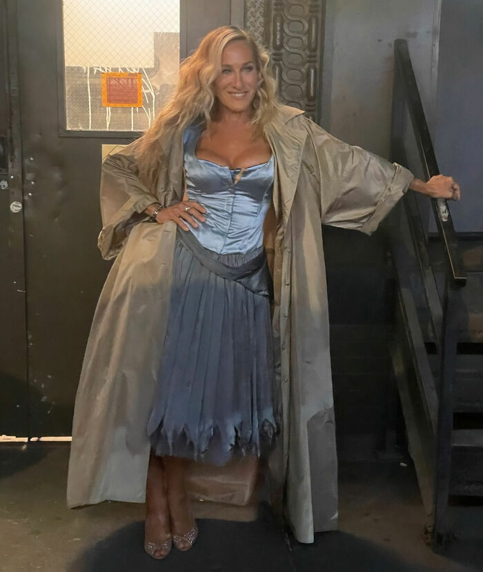 Mulher com vestido de cetim azul e casaco bege posando dentro de casa, relacionada a Chris Noth quebrando o silêncio após reação dos fãs. Mulher com vestido de cetim azul e casaco bege posando dentro de casa, relacionada a Chris Noth quebrando o silêncio após reação dos fãs.