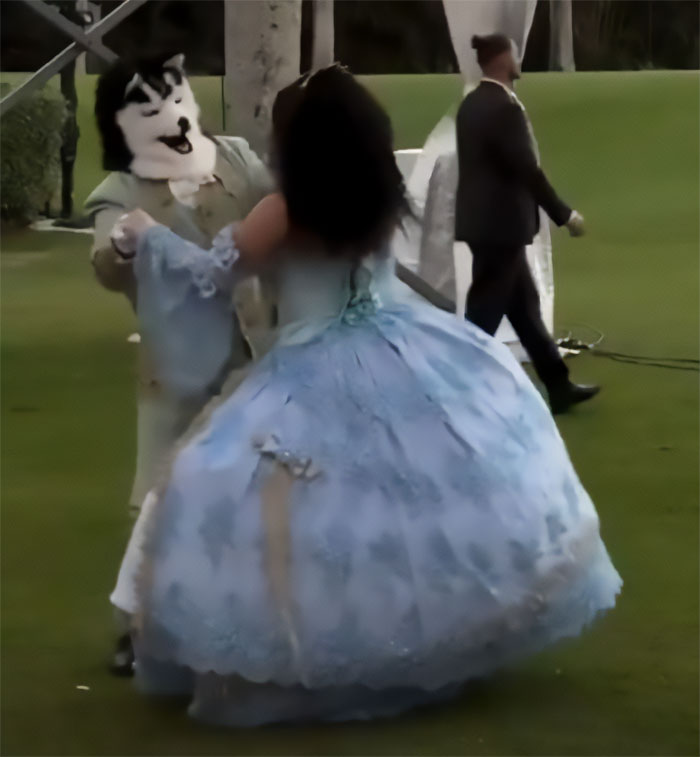 Person in dog mask dancing with woman in old-time blue costume at a creepy Mar-a-Lago event outdoors on grass. Person in dog mask dancing with woman in old-time blue costume at a creepy Mar-a-Lago event outdoors on grass.