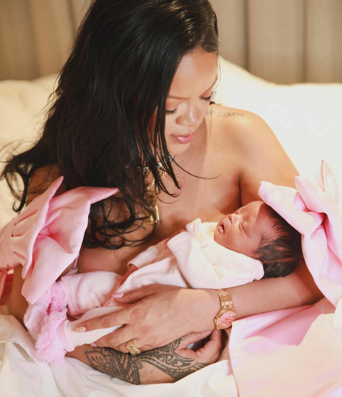Woman cradling newborn in pink outfit on bed, linked to distorted lingerie photos controversy Woman cradling newborn in pink outfit on bed, linked to distorted lingerie photos controversy