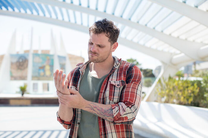 Man in a plaid shirt outdoors experiencing a painful moment, reflecting on wait that is not normal moments.