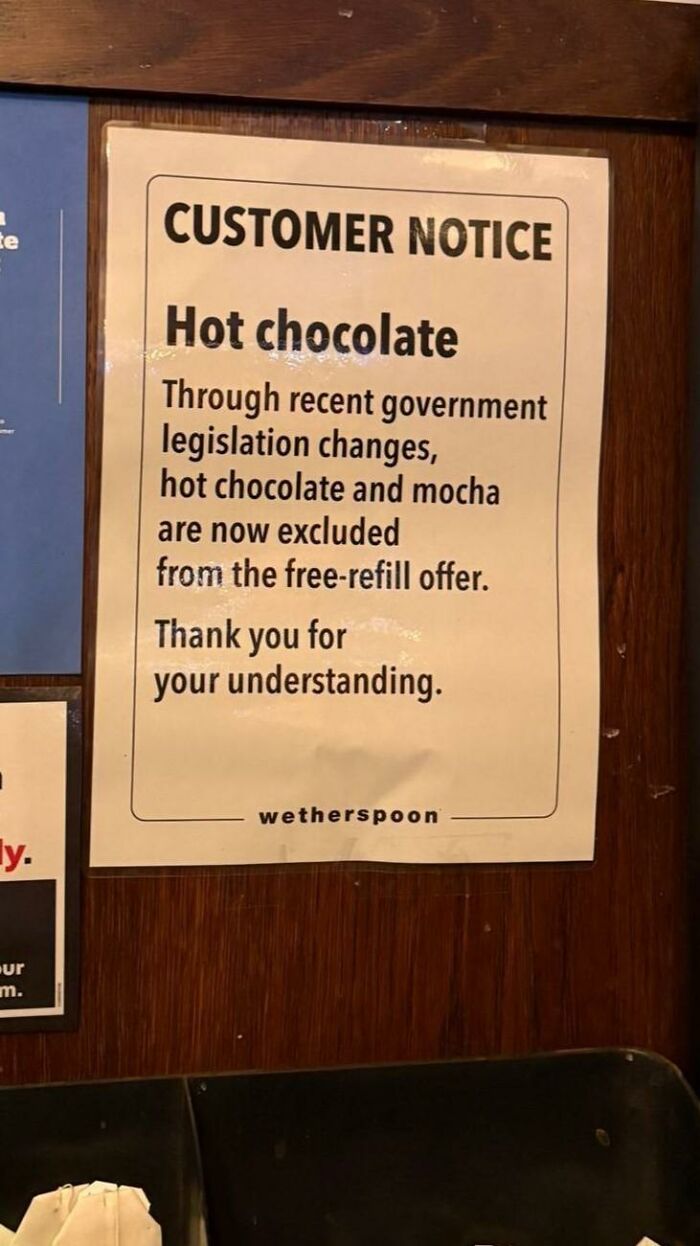 Customer notice at Wetherspoon explaining hot chocolate excluded from free refills due to recent legislation in Europe.