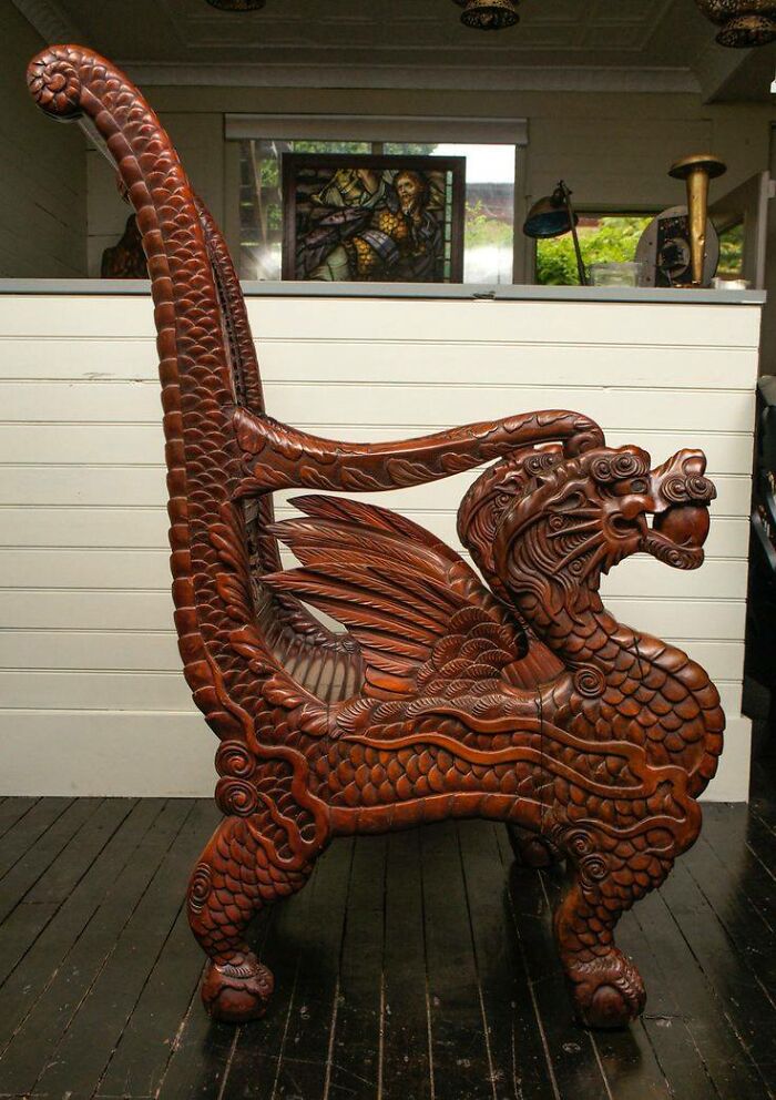 Intricately carved woodworking project of a dragon-shaped wooden chair with detailed scales and wings.
