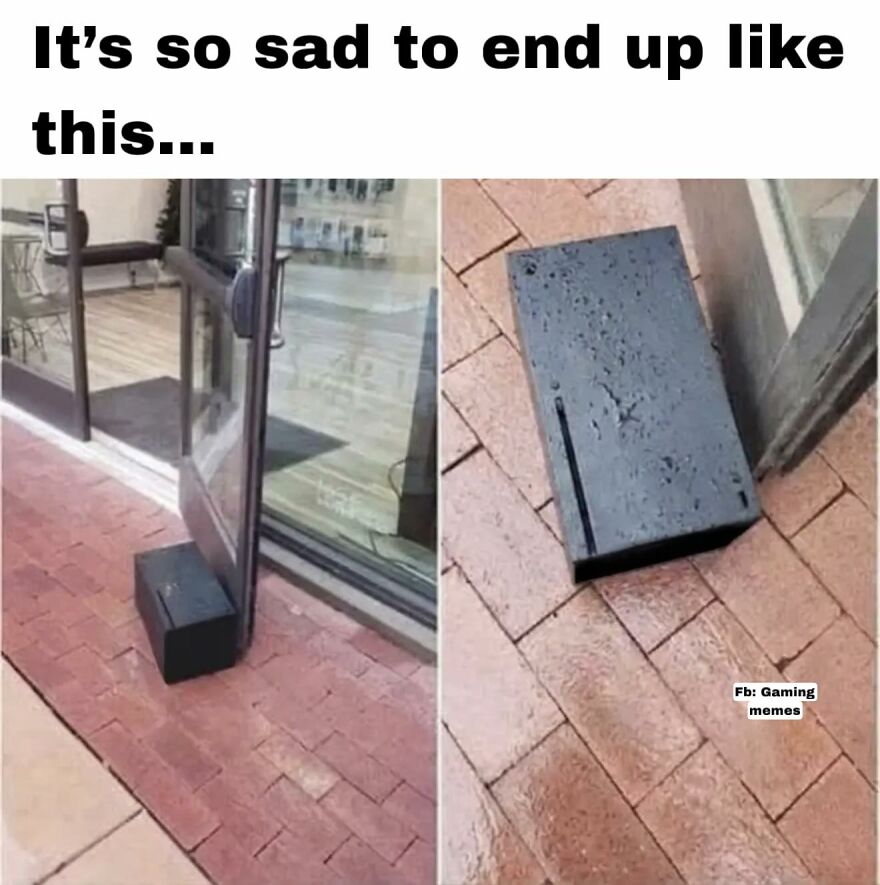Black gaming console used to hold a door open on a wet brick sidewalk, relatable meme for exhausted adults who play video games.