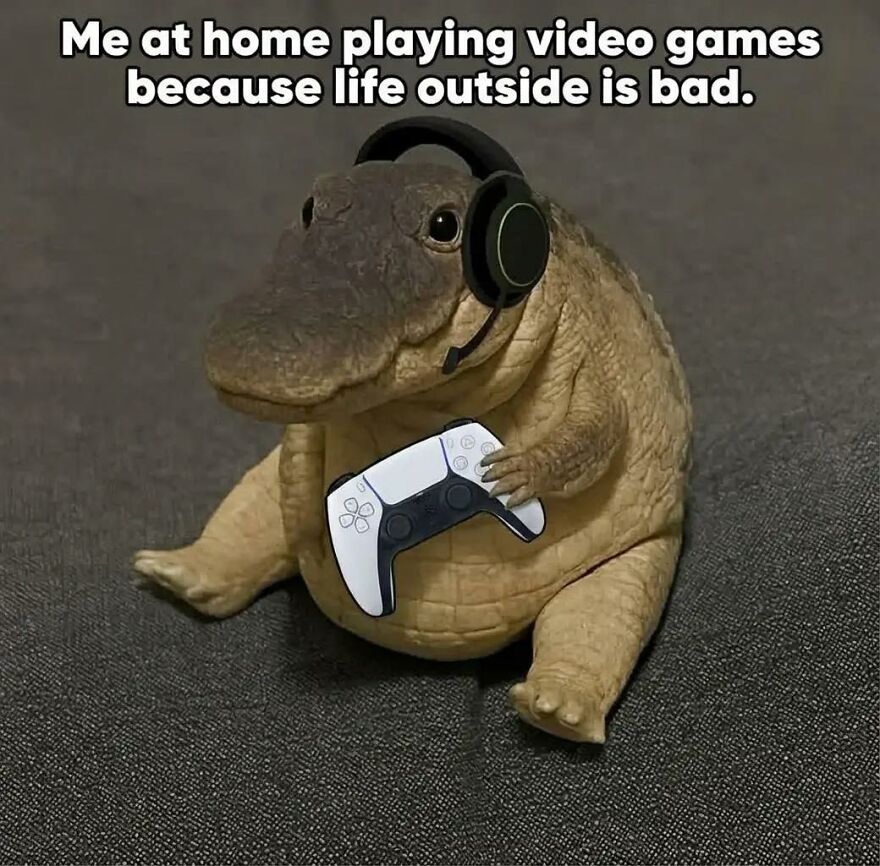 A small plush crocodile wearing a headset and holding a video game controller, symbolizing exhausted adults playing games.