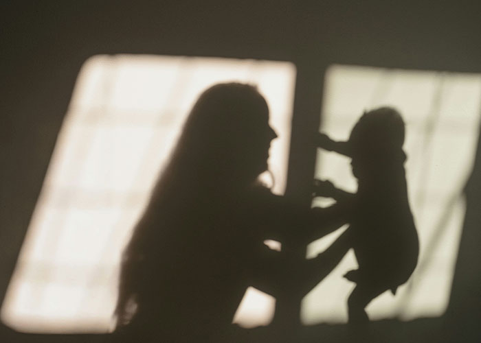 Silhouette of a father holding a baby, highlighting issues related to changing gender identity and child support.