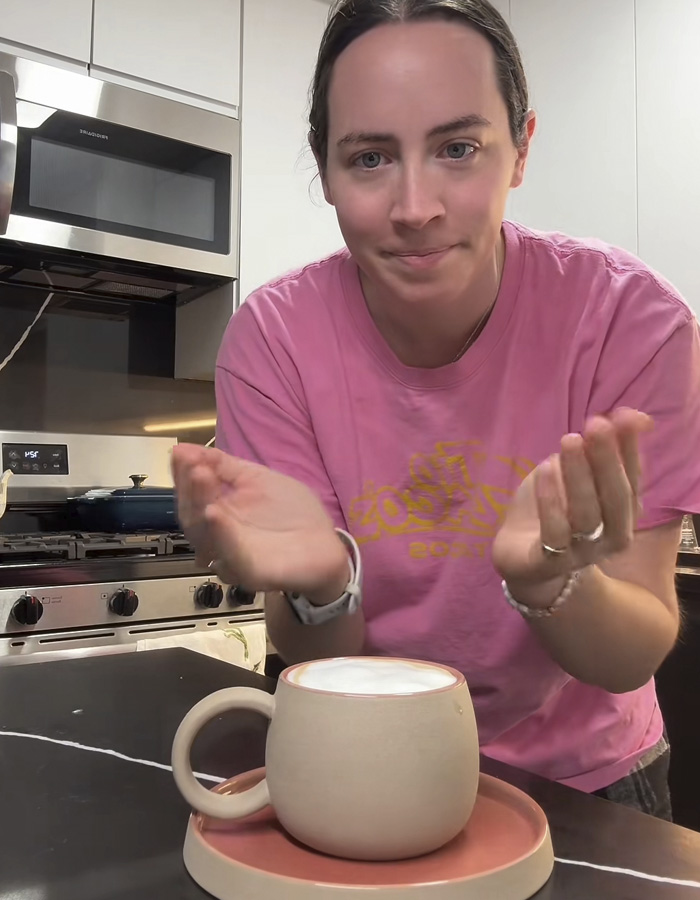 Woman in pink shirt presenting a ceramic mug gift sparking a huge relationship debate online about fiancé’s intentions. Woman in pink shirt presenting a ceramic mug gift sparking a huge relationship debate online about fiancé’s intentions.