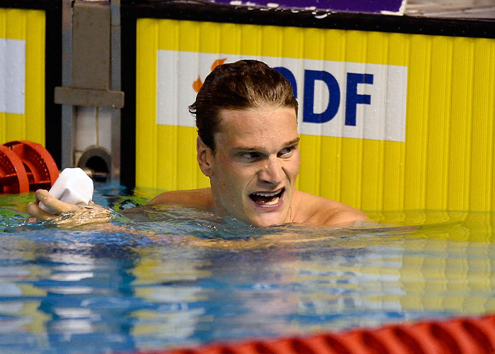 Olympic gold medalist swimmer in pool showing emotion after a race, related to crime charge against former coach's daughter.