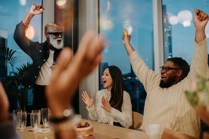 A diverse group of friends laughing and raising hands around a table, enjoying paranoia questions game night. A diverse group of friends laughing and raising hands around a table, enjoying paranoia questions game night.