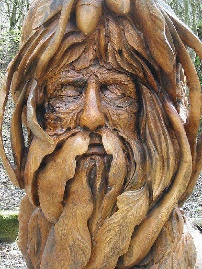 Intricately carved woodworking project depicting a detailed wooden face with leaves and natural elements.