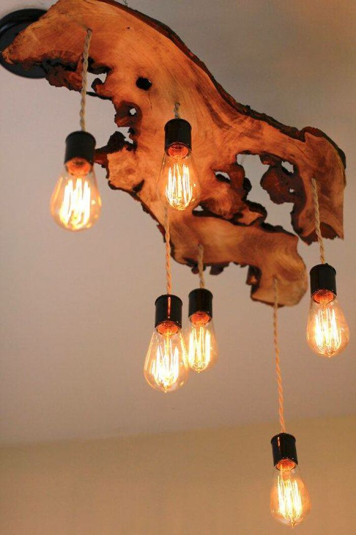 Rustic wooden chandelier crafted from natural wood slab with multiple vintage Edison bulbs hanging from cords.
