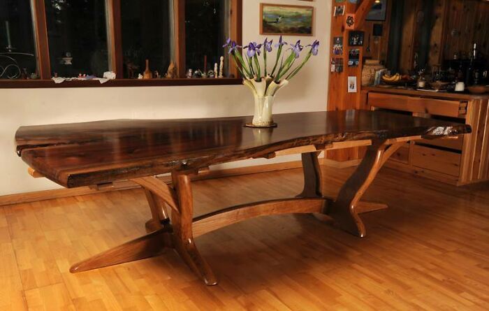Handcrafted wooden dining table with natural live edge design and smooth polished finish in a cozy room setting.