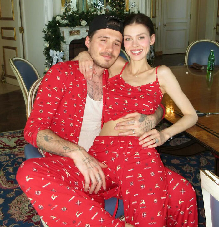 Brooklyn Beckham wearing matching red pajamas with partner in a cozy indoor setting during a family feud period. Brooklyn Beckham wearing matching red pajamas with partner in a cozy indoor setting during a family feud period.