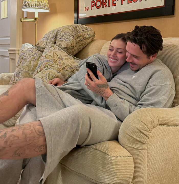 Couple in casual gray loungewear relaxing on a couch, illustrating Brooklyn Beckham's biting accusations against parents controversy.