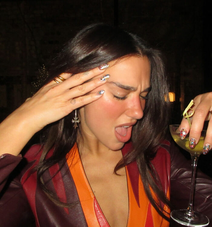 Dua Lipa looking stunned while holding a cocktail, reacting to a South African fan using a filter on their selfie together.