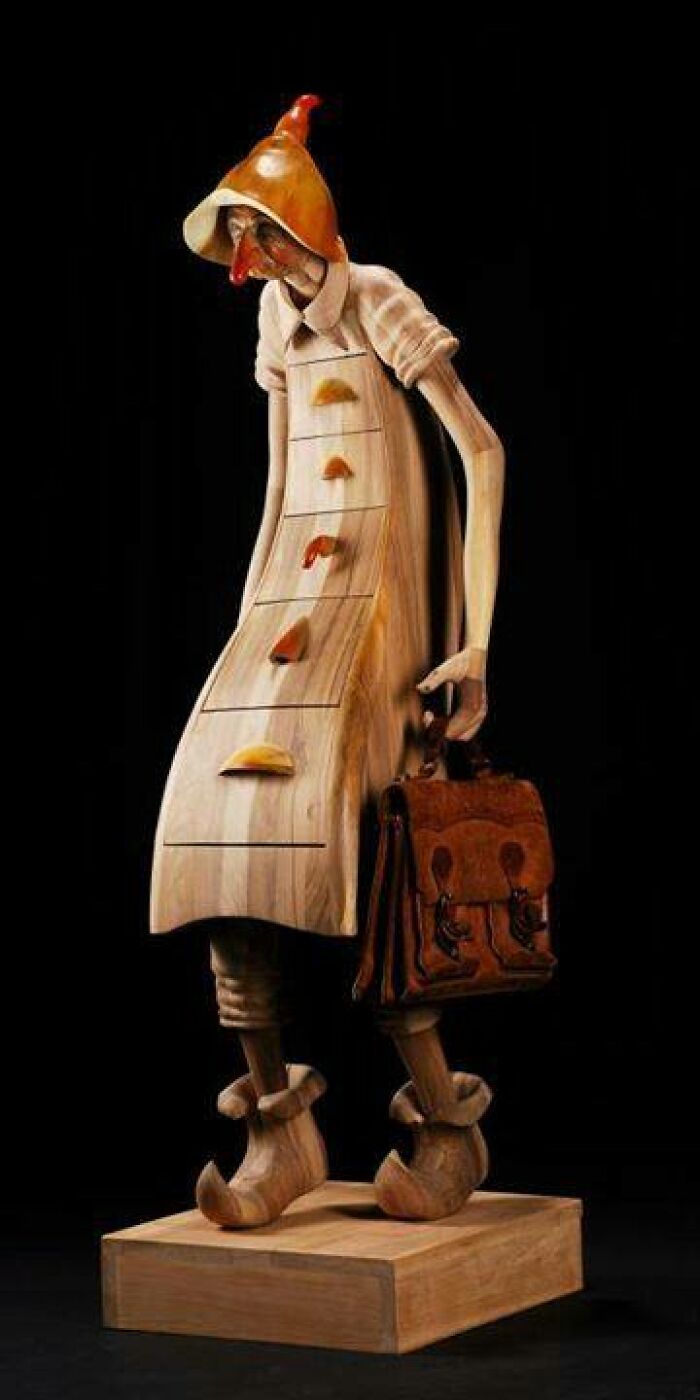 Wooden sculpture of a whimsical character with drawers for a body and carrying a detailed carved briefcase, woodworking project.